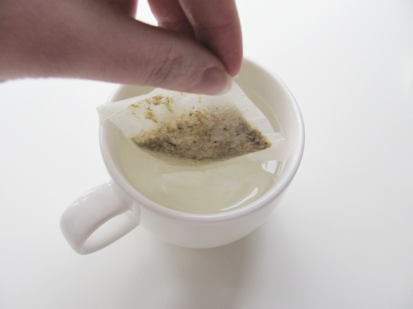 Use your fingers to drop tea bag into water